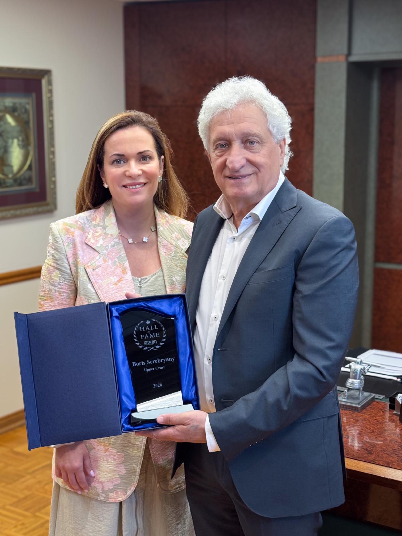 Boris Serebryany holding the Gorcery Business Hall of Fame Award with Upper Crust President Carmela Serebryany