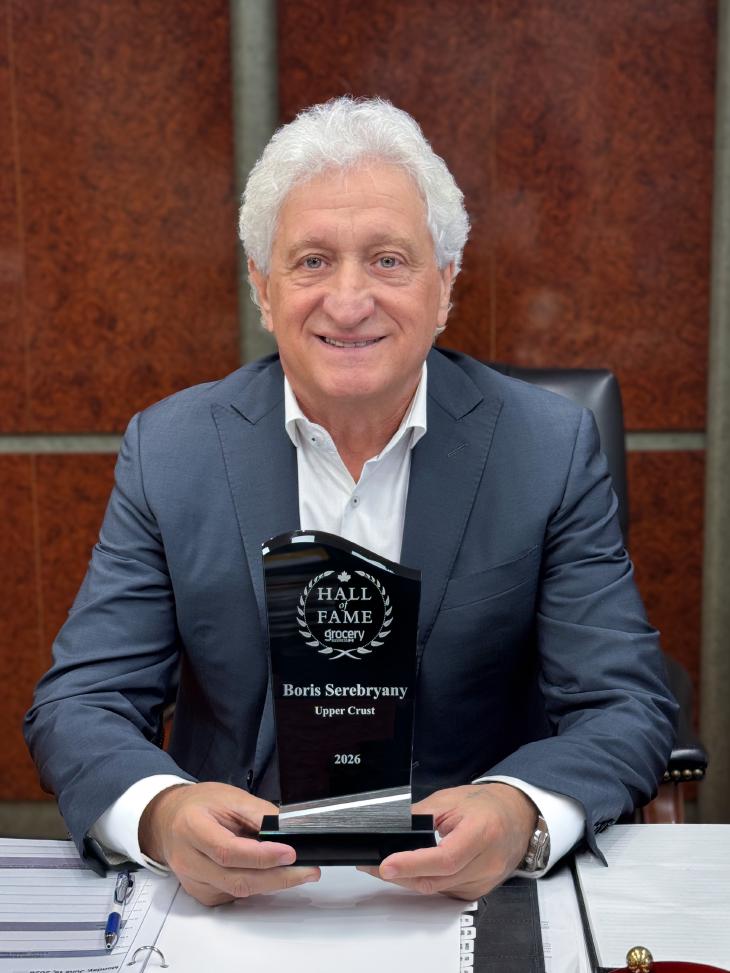 Boris Serebryany at his desk holding the Gorcery Business Hall of Fame Award